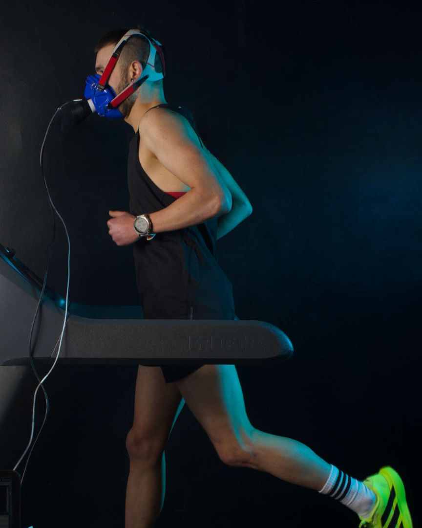 Person running on a treadmill wearing a blue mask in a dark room