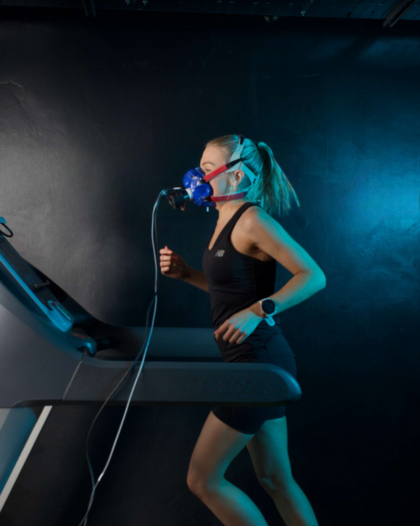 Person on a treadmill wearing an oxygen mask in a dark room