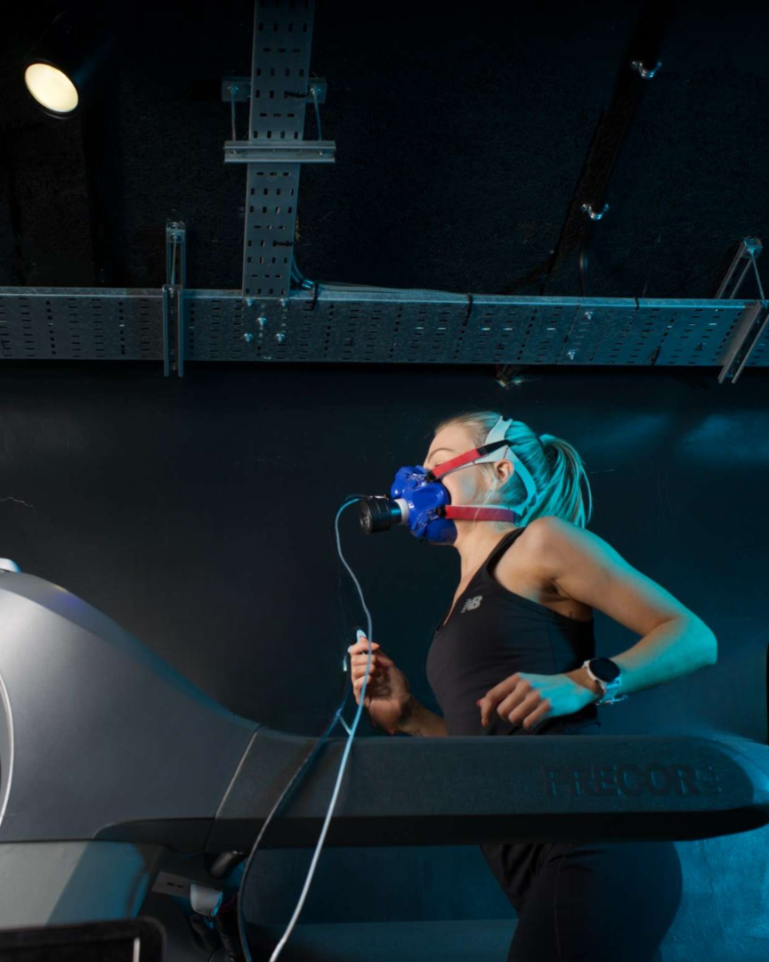 Person using a treadmill with a mask on in a dark room