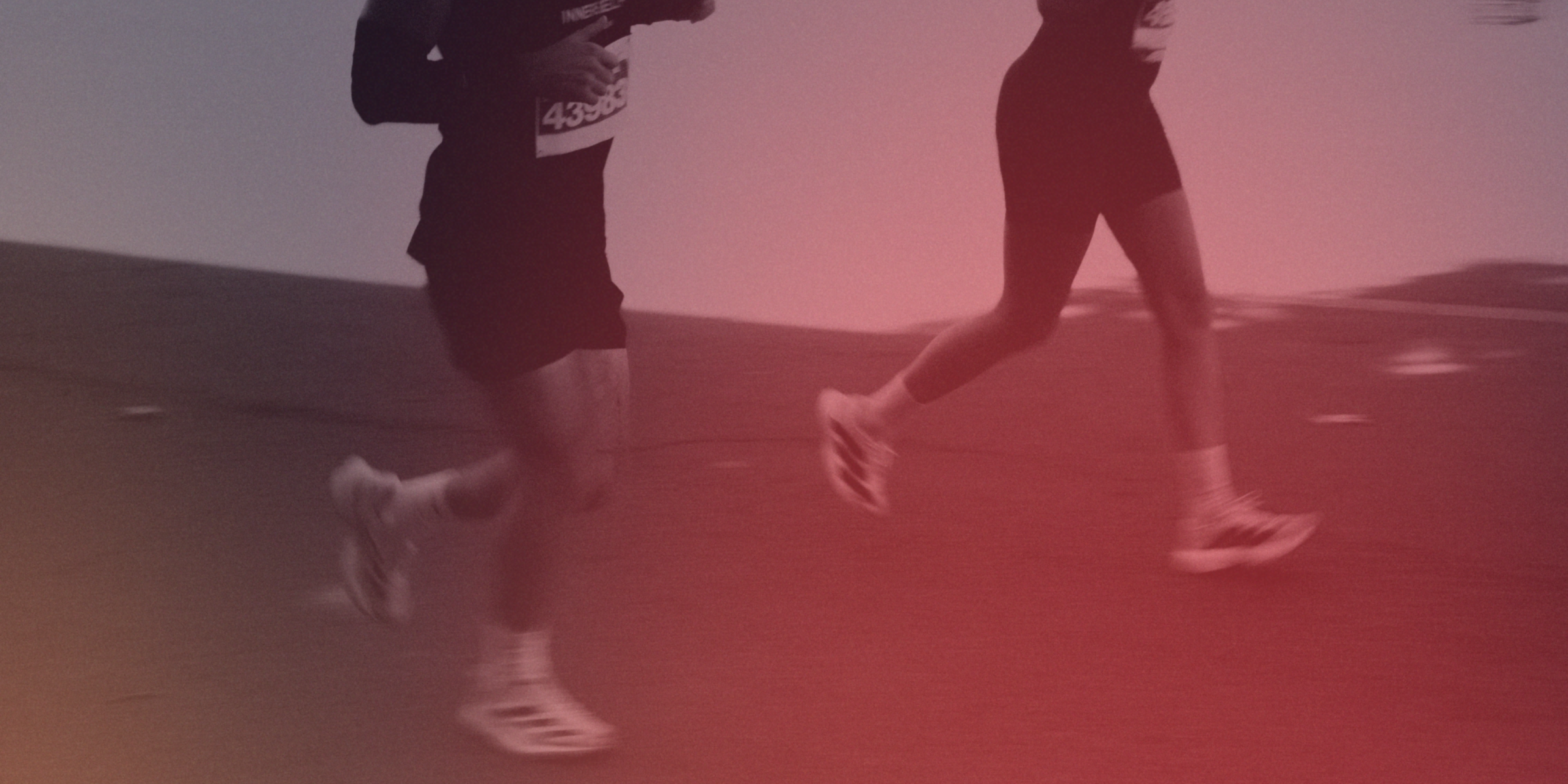 Two people running on a track with a red filter applied